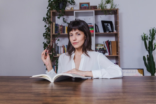 Mujer con libro sujetando gafas