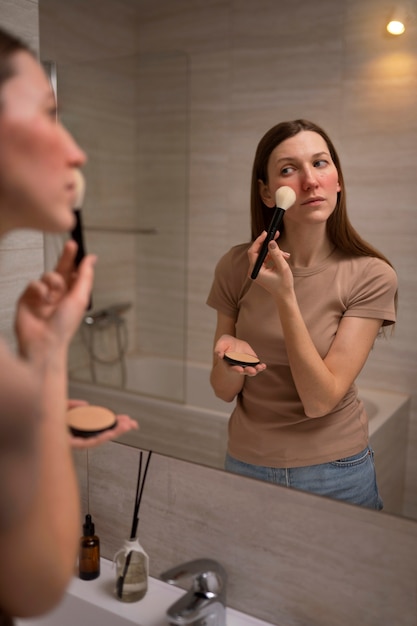 Foto gratuita mujer lidiando con rosácea aplicando maquillaje con cepillo