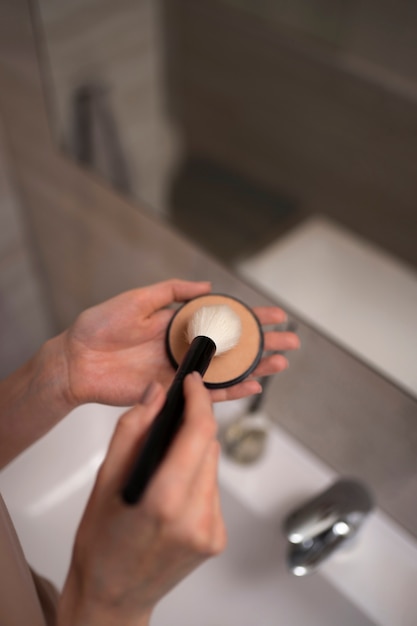 Foto gratuita mujer lidiando con rosácea aplicando maquillaje con cepillo