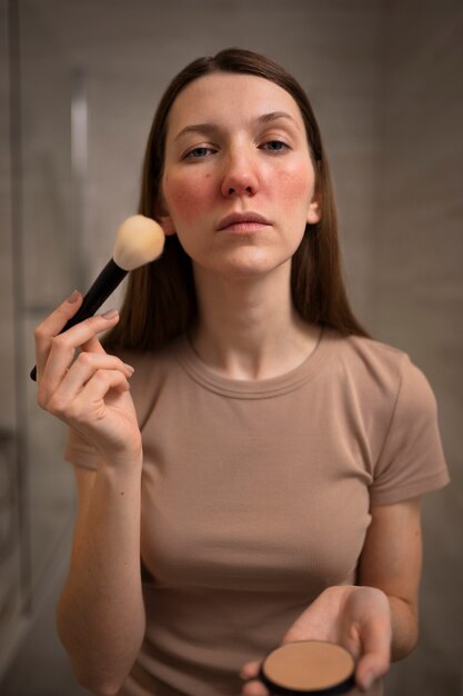 Mujer lidiando con rosácea aplicando maquillaje con cepillo