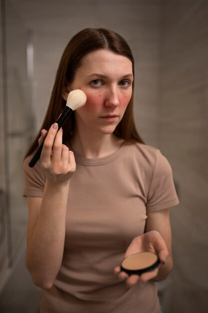 Mujer lidiando con rosácea aplicando maquillaje con cepillo