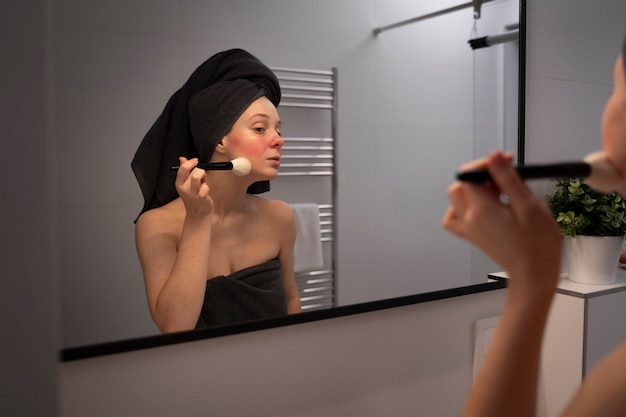Mujer lidiando con rosácea aplicando maquillaje con cepillo