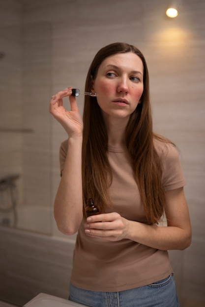 Foto gratuita mujer lidiando con rosácea usando suero para la piel