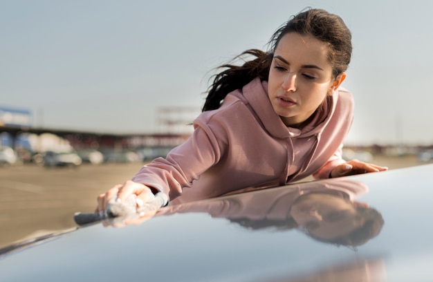 Mujer limpiando el capó del coche