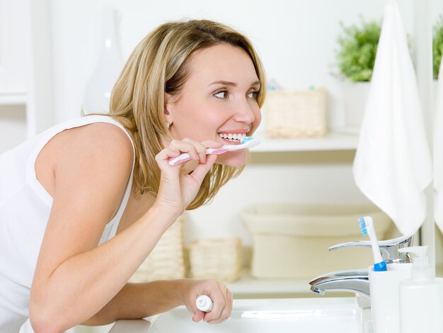 Mujer limpiando los dientes con cepillo de dientes