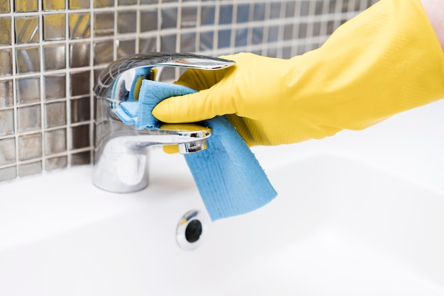 Mujer limpiando el lavabo en el baño.