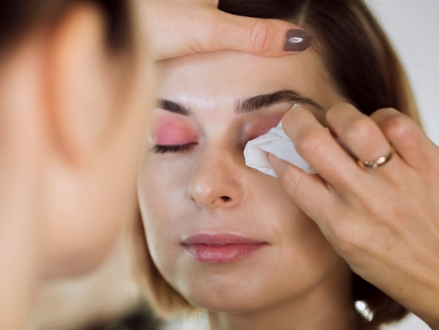 Mujer limpiando maquillaje de ojos de modelo