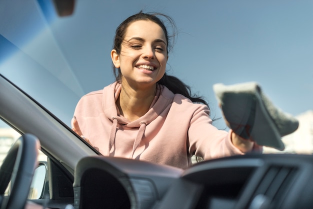 Mujer limpiando el parabrisas delantero de su automóvil