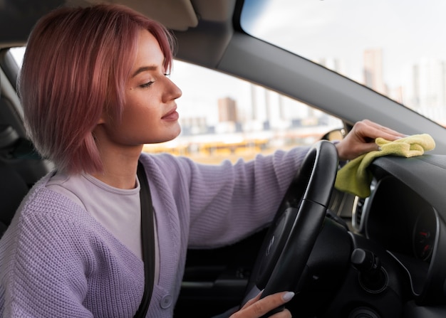 Mujer limpiando el salpicadero de su coche con un trapo