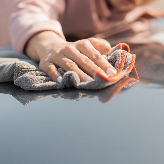 Mujer limpiando su auto con un paño