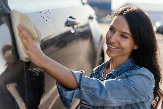 Foto gratuita mujer limpiando su coche fuera