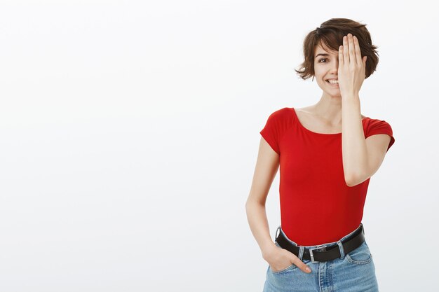 Mujer linda divertida cubre la mitad de la cara y sonriendo