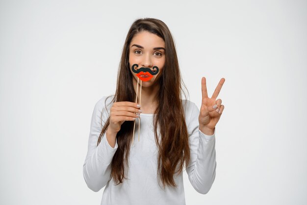 Mujer linda divertida con labios falsos y bigote, muestra paz