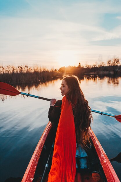 Mujer linda feliz que sostiene la paleta en un kayak en el río