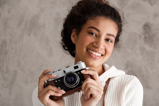 Mujer linda inconformista tomando fotos en cámara retro