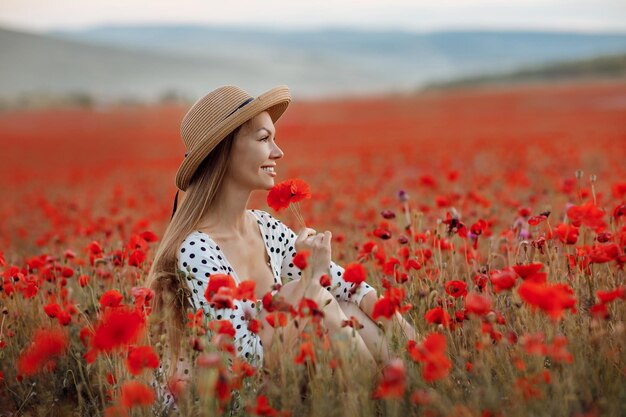 Mujer linda joven en un campo de amapolas