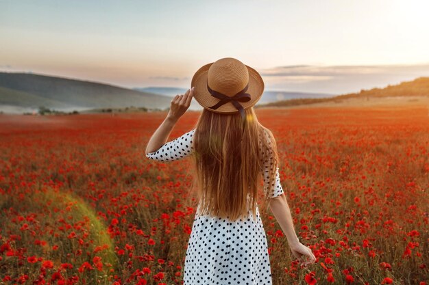 Mujer linda joven en un campo de amapolas