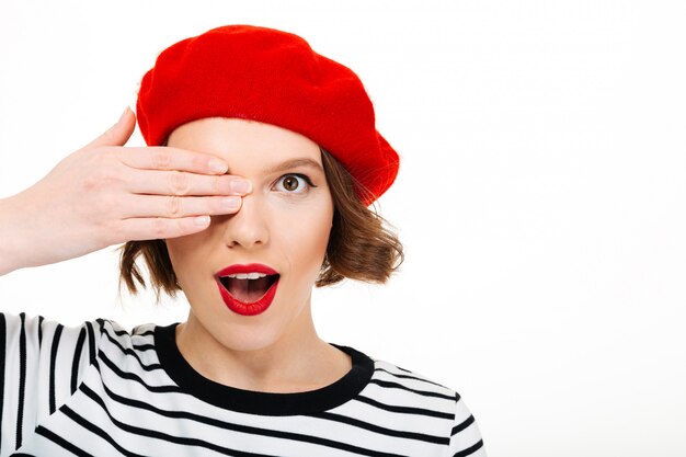 Mujer linda joven que cubre el ojo con la mano.