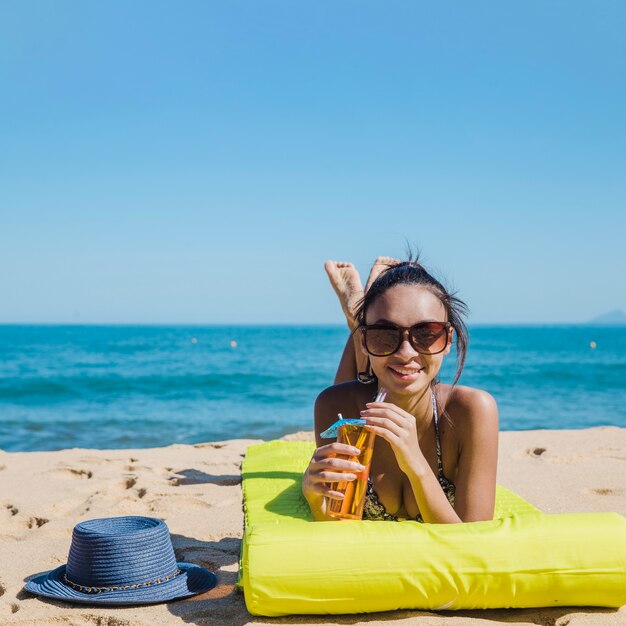 Mujer linda en la playa con cocktail