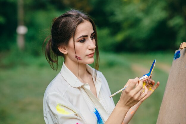 Mujer llenando su pincel de pintura azul