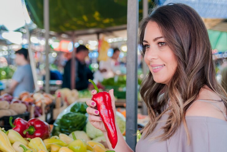 Una mujer lleva pimientos en sus manos. Mujer, elegir, fresco, vegetales, medición, tienda de comestibles