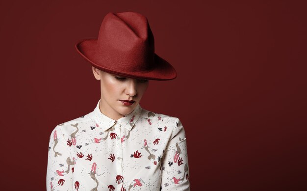 Mujer lleva un sombrero rojo sobre un fondo rojo.