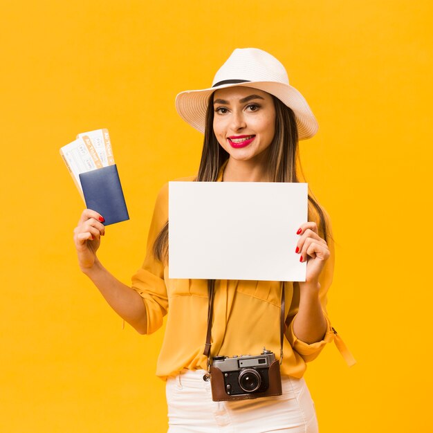 Mujer llevando una cámara y sosteniendo pasajes de avión y pasaporte