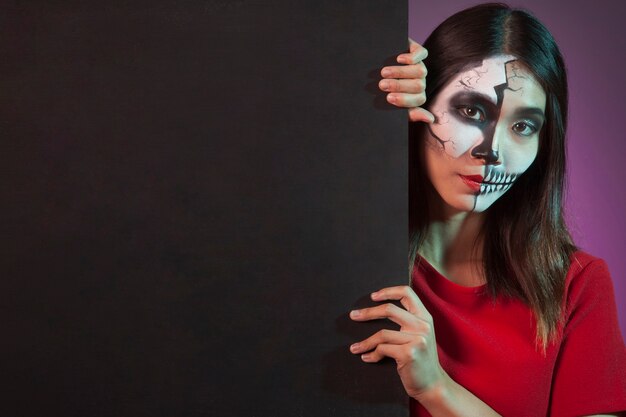 Mujer llevando disfraz de halloween detrás de pared