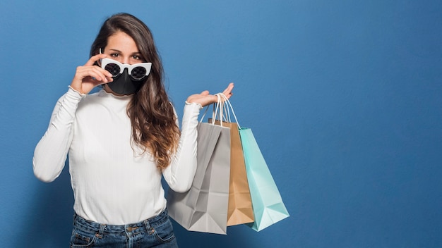 Mujer, llevando, máscara, y, tenencia, bolsas de compras