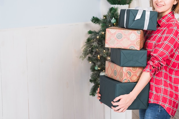 Mujer llevando montón de cajas de regalo