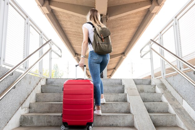 Mujer llevando su equipaje en las escaleras