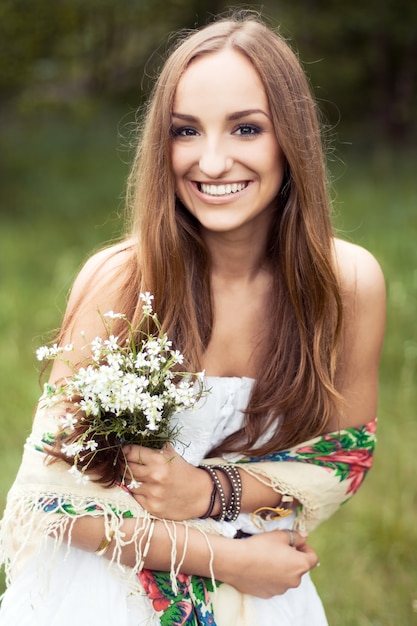 Mujer llevando un vestido blanco y sujetando flores