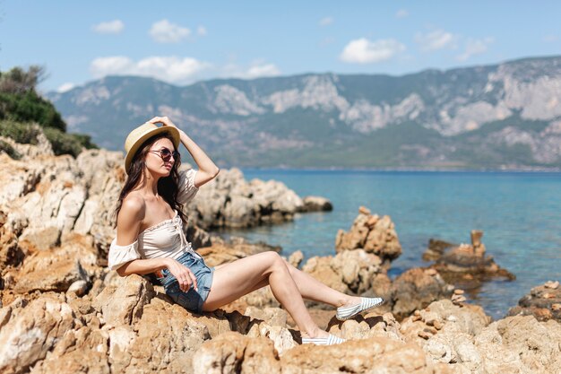 Mujer, llevar lentes de sol, posición, en, rocas