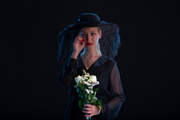 Mujer llorando vestida de negro con flores sobre la superficie negra muerte tristeza funeral