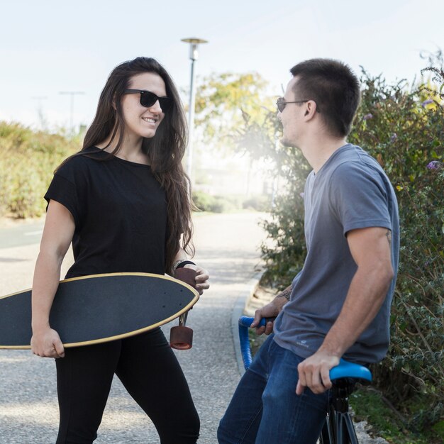 Mujer con longboard y hombre con bicicleta