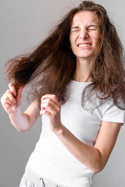 Foto gratuita mujer lucha por cepillarse el pelo