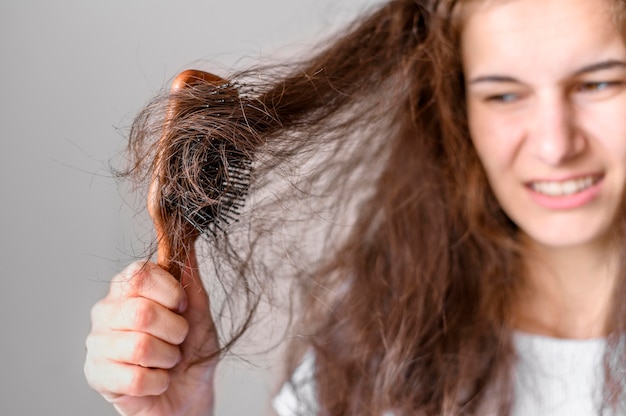 Foto gratuita mujer luchando por cepillarse el pelo