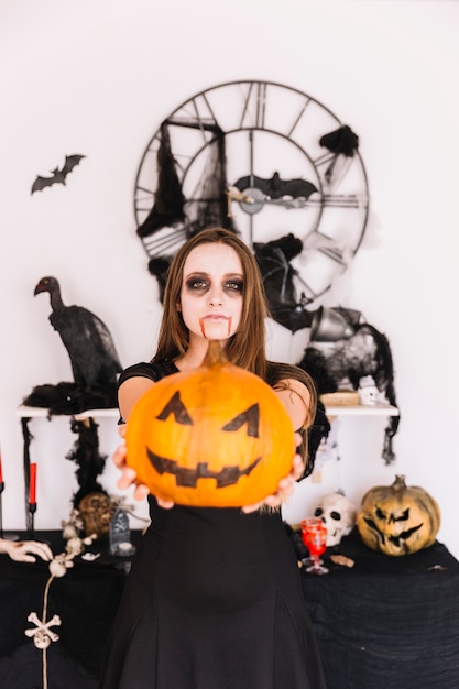 Foto gratuita mujer en lugar de halloween decorado con calabaza