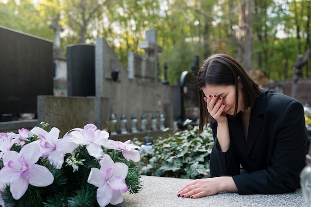 Mujer de luto en el cementerio junto a la tumba