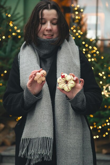 Foto gratuita mujer con macarrones de navidad en un fondo borroso de árboles de navidad