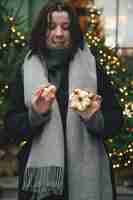 Foto gratuita mujer con macarrones de navidad en un fondo borroso de árboles de navidad