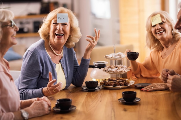 Foto gratuita una mujer madura alegre jugando a las adivinanzas con sus amigos y divirtiéndose en casa