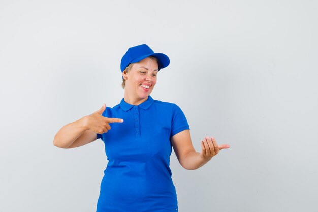 Mujer madura con camiseta azul apuntando a algo que fingió ser retenido y parecía contento.