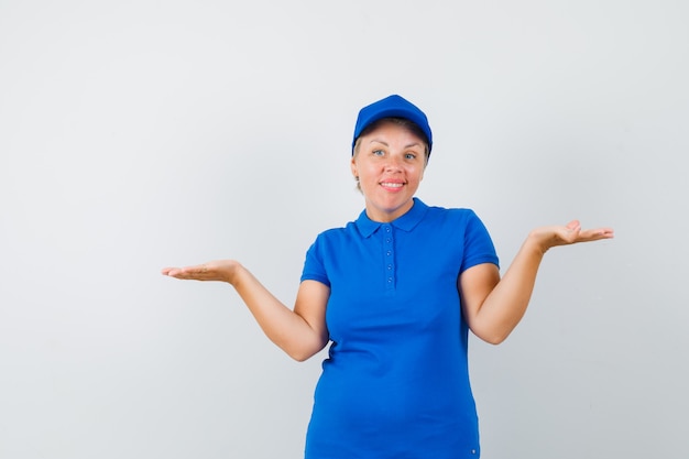 Mujer madura en camiseta azul que muestra un gesto de impotencia y parece confundido.