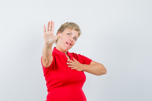 Mujer madura en camiseta roja mostrando gesto de parada