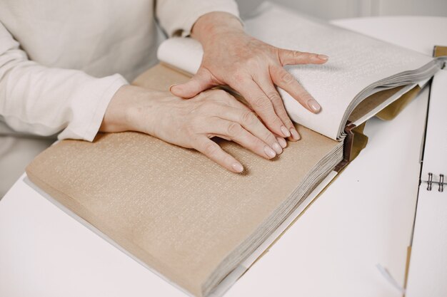 Mujer madura ciega leyendo un libro en braille en casa