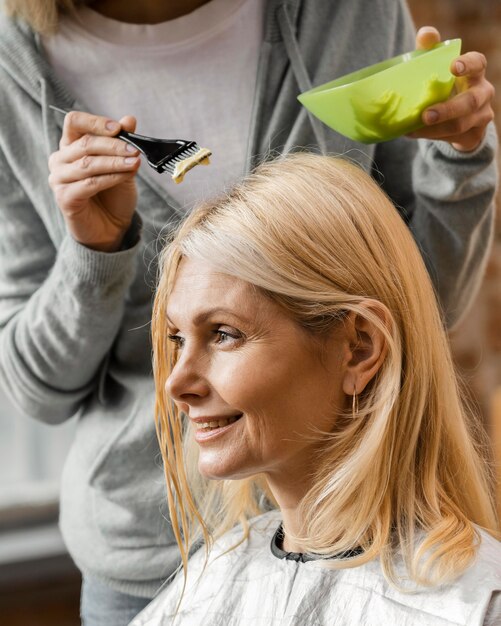 Mujer madura conseguir su cabello teñido por peluquero en casa