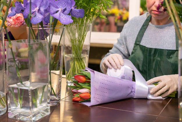 Mujer madura envolviendo ramo con tulipanes