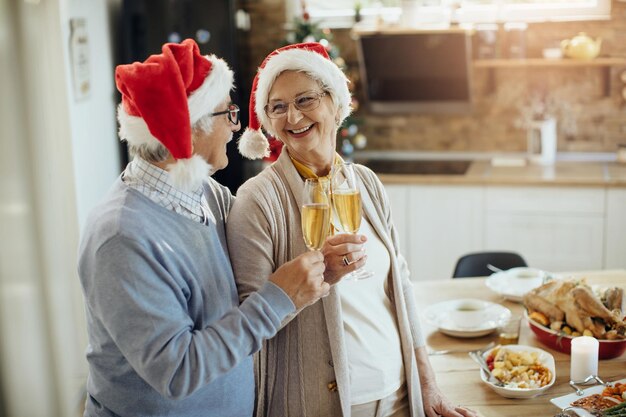 Mujer madura feliz brindando con su esposo mientras celebra la Navidad en casa