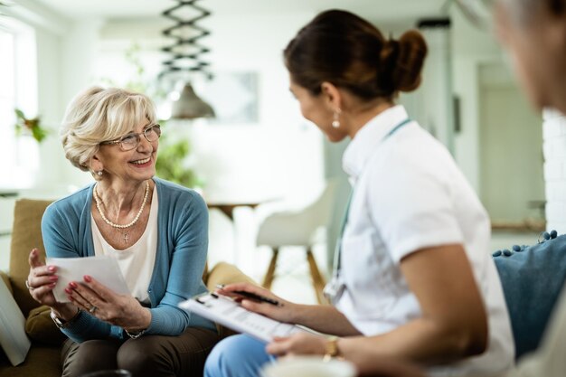 Mujer madura feliz comunicándose con una doctora en casa